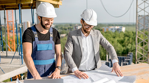 Two men wearing hard hat looking at the floor plan photo